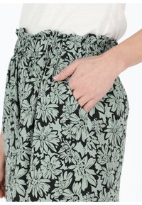 Gonna con stampa floreale caratterizzata da una vita arricciata, tasche laterali, in una combinazione di verde menta e nero con audaci motivi floreali.