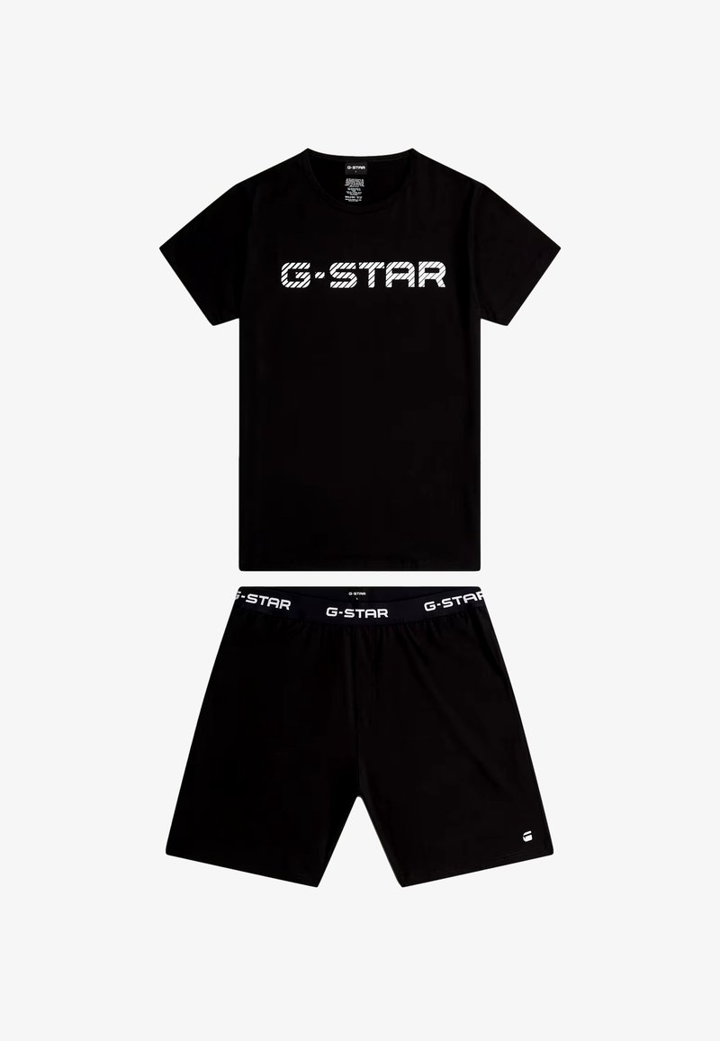 Camiseta de manga corta negra con la marca G-Star, acompañada de pantalones cortos negros a juego que presentan un logo de G-Star en la cintura y un pequeño logo en la pierna.