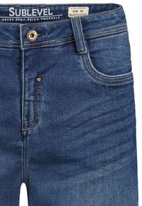 Blaue Denim-Jeans mit verblasstem Wasch-Effekt, ausgestattet mit einem Knopfverschluss vorne, fünf Taschen und kontrastierenden Nähdetails. Größe-Etikett enthalten.