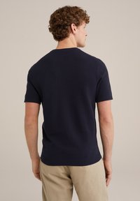 Navy knit short-sleeve sweater featuring a crew neck, textured fabric, ribbed cuffs, and hem, paired with light-colored trousers.