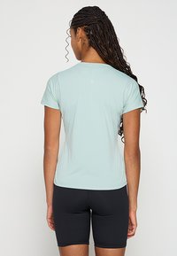 Jasnoniebieska koszulka sportowa z krótkimi rękawami, z teksturowanym materiałem i dopasowanym fasonem, zestawiona z czarnymi szortami.