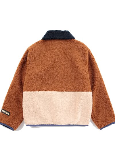 Veste en polaire bicolore avec partie supérieure marron, partie inférieure beige, col marine et petite étiquette noire sur le poignet de la manche gauche.