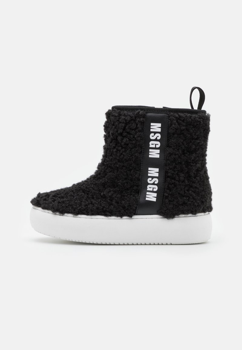 Botas de tornozelo pretas com uma textura felpuda, sola de borracha branca e uma tira lateral com o texto "MSGM". Laço na parte de trás para fácil uso.