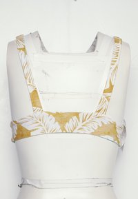 Top cropped com padrão floral amarelo e branco, com alças largas e costas planas. Feito de um tecido leve com acabamento texturizado.
