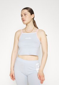 Ljusblå croppad linne med rosa kant, med en framlogotyp. Mjuk tyg med en figurnära design, kombinerad med matchande ljusblå leggings.