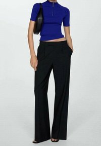 Niebieska prążkowana bluzka z krótkimi rękawami i zamkiem błyskawicznym, w zestawie z czarnymi spodniami o szerokich nogawkach, z przodu z plisami i bocznymi kieszeniami.