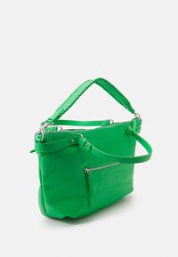 Sac à main en cuir vert avec poignées tressées, poches zippées et ferrures métalliques. Texture douce, design structuré et taille moyenne.