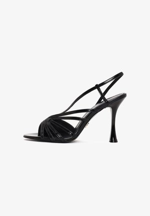 Sandalia de charol negro con tacón alto, varias tiras finas y diseño tipo slingback sobre un fondo blanco.