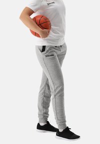 Grijze joggingbroek met zwarte accenten, elastische boorden en twee zijzakken. Gecombineerd met een wit Spalding T-shirt en zwarte sportschoenen.