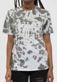 Gray and white tie-dye cotton t-shirt with a graphic print in white and red featuring abstract figures and text. Short sleeves and round neckline.