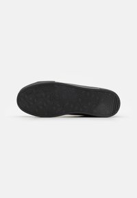 Suela de zapato negra con un patrón geométrico hexagonal, hecha de goma con una textura antideslizante para tracción y estabilidad.