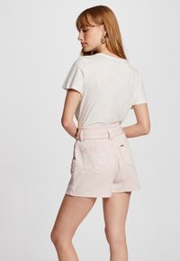 Light pink denim shorts with a belted waist and two back pockets. Soft texture and straight cut design. Short length with minimal detailing.
