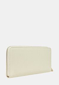 Portafoglio con zip in morbida pelle testurizzata color crema; forma rettangolare con angoli arrotondati e dettaglio di cucitura visibile lungo la zip.