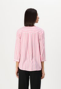 Rutet skjorte med rosa og hvite vertikale striper, trekvart ermer og avrundet kant. Laget av lett materiale med en avslappet passform.