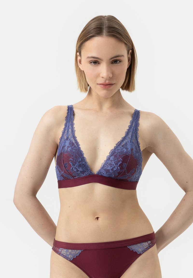 Světlá krajková braletka v modré barvě s hlubokým výstřihem do V, vybavená vínovou páskou pod prsy. Doplněné o odpovídající vínové kalhotky s krajkovými akcenty.