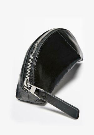 Black leather pouch with a curved design, silver zipper, and flat strap. Smooth texture with subtle sheen.