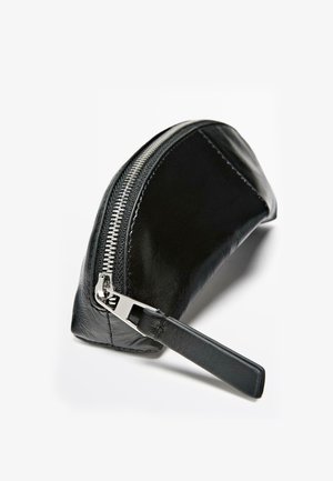 Schwarze Lederetui mit geschwungenem Design, silbernem Reißverschluss und flachem Riemen. Glatte Textur mit dezentem Glanz.