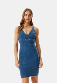 Denim dress with a fitted silhouette, V-neckline, narrow shoulder straps, and a decorative silver clasp at the waist. Smooth texture, dark blue color.