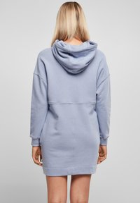 Svijetloplavi dukserica haljina s kapuljačom, s rebrastim manžetama, opuštenim krojem i ravnim rubom. Mekani materijal, minimalistički dizajn s detaljima šivanja.