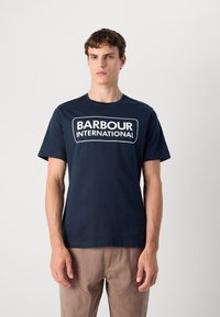 Ναυτικό μπλε βαμβακερό T-shirt με λευκό λογότυπο "BARBOUR INTERNATIONAL" μπροστά, στρογγυλή λαιμόκοψη και κοντά μανίκια.
