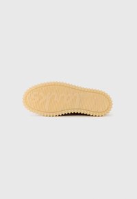 Gummisåle i beige med teksturerte spor og et hevet logo-mønster, med avrundet kant og distinkt grepdesign.