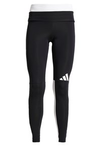 Czarne legginsy sportowe z białym paskiem w talii. Posiadają jednolitą konstrukcję z białym akcentem i logo na dolnej części nogawki. Gładki, elastyczny materiał.
