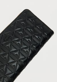 Mustast nahast rahakott geomeetrilise reljeefse mustriga, millel on tõmblukuga kinnis ja esiküljel logodeetailid.