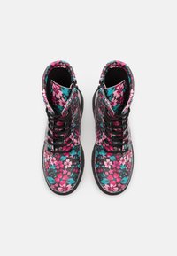 Bottes à motif floral avec une base noire, ornées de fleurs roses et bleu sarcelle. Design montants avec lacets et col rembourré. Semelle en caoutchouc.
