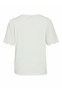 Camiseta blanca de manga corta con cuello redondo y detalle de ojal en los puños. Tejido de algodón suave, corte relajado y sin logotipos visibles.