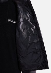 Veste noire ouverte pour montrer la doublure intérieure lisse et brillante sur le côté droit et le tissu polaire noir avec le logo Napapijri blanc sur le côté gauche.
