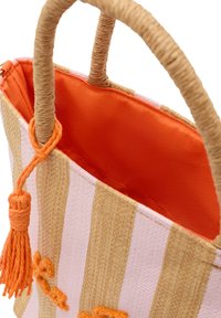 Vävd halmhandväska med orange inredning och randig beige och vit utsida. Har en tofsdekoration och stadiga vävda handtag.