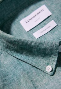 Slim-fit skjorta i bomull och linne i grön färg, med krage med knappar, subtil textur och etiketter för märke och material inuti kragen.