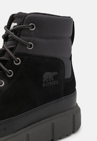 Stivale in suede nero e tessuto grigio testurizzato con occhielli in metallo, lacci rotondi e una spessa suola in gomma grigia. Presenta il logo del marchio impresso.