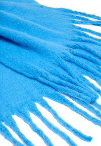 Sciarpa morbida in lana blu con frange lunghe e spesse, stesa su uno sfondo bianco.