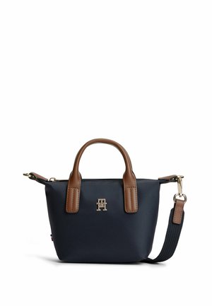 Kleine dunkelblaue Handtasche mit braunen Ledergriffen, einem abnehmbaren dunkelblauen Trageriemen und einem Metalllogo auf der Vorderseite.