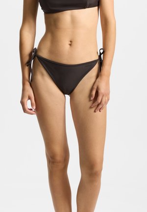 Parte inferior de bikini negra con lazos ajustables en los laterales, diseño de tiro bajo y textura suave. Cuenta con una marca sutil en la cintura.