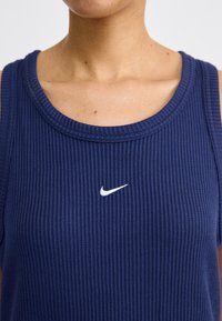 Tamno plava, rebrasta atletska majica bez rukava s okruglim izrezom i malim bijelim Nikeovim logotipom na prsima.
