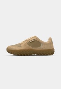 Beige athletic shoes with a textured upper, round toe, and a rubber sole featuring small, raised patterns for traction. Brand logo on side.