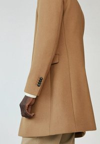 Kamelfarvet frakke med skræddersyet pasform, der har en enkelt knap ved manchetten, sidelomme og struktureret uldblandingsstof.