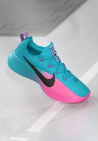 Blå og pink Nike løbesko med sort swoosh-logo og unikke snoede snørebånd på en lys grå overflade.