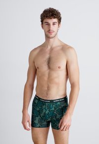 Dunkelgrüne Herren-Boxershorts mit tropischem Blattmuster, elastischer schwarzer Bund mit "BJÖRN BORG" Logo, Baumwollmaterial, enganliegendes Design.