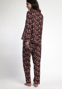 Conjunto de pijama marrón con mangas largas y pantalones, que presenta un divertido patrón de dibujos animados. Tejido suave, ajuste relajado y puños acanalados.