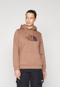 Felpa marrone con tasca frontale, cappuccio regolabile con cordino e stampa del logo nera. Realizzata in materiale morbido, presenta un design semplice con polsini a coste.