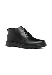Botas de tobillo de cuero negro con un acabado suave, diseño con cordones y suela de goma que cuenta con un dibujo para mayor tracción. Forma y detalles minimalistas.