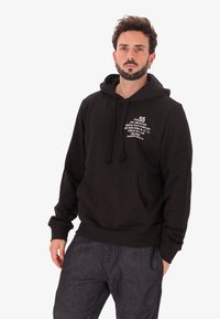 Felpa nera con cappuccio e lacci, tasca frontale e testo stampato bianco sul petto. Presenta polsini e orlo a coste, realizzata in tessuto morbido.