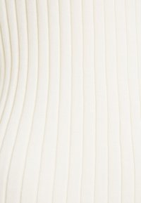 Žebrovaná pletenina v krémové barvě s vertikálními pruhy. Textura je měkká a elastická, s hladkým povrchem.