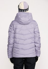 Lys lilla pufferjakke med vandret syninger, aftagelig hætte og elastiske manchetter, parret med en strikket lys og mørk hat.
