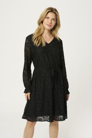 Black lace dress with long sleeves, V-neck, cinched waist, and layered skirt. Features intricate cut-out patterns and ruffled sleeve cuffs.