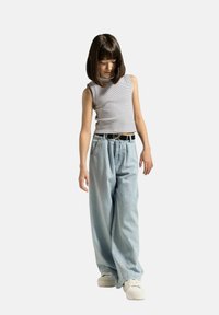 Jasnoszary bezrękawnik w paski, luźne jasnoniebieskie d�żinsy z elastycznym paskiem, czarny pasek i białe trampki.