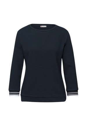Pull bleu marine texturé à manches longues avec encolure ronde et poignets blancs ornés de rayures noires sur fond blanc.